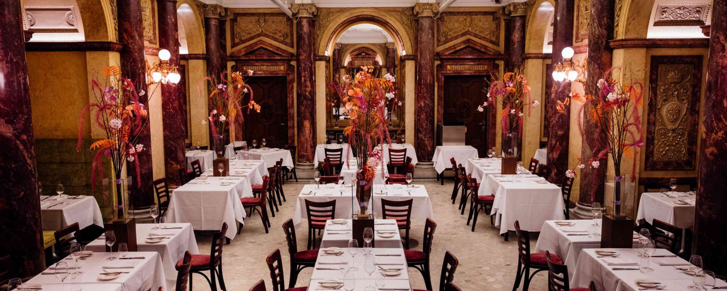 Klimatisierter Marmorsaal des Restaurants Vestibül im Wiener Burgtheater mit historischen Säulen und gedeckten Tischen.