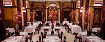 Klimatisierter Marmorsaal des Restaurants Vestibül im Wiener Burgtheater mit historischen Säulen und gedeckten Tischen.