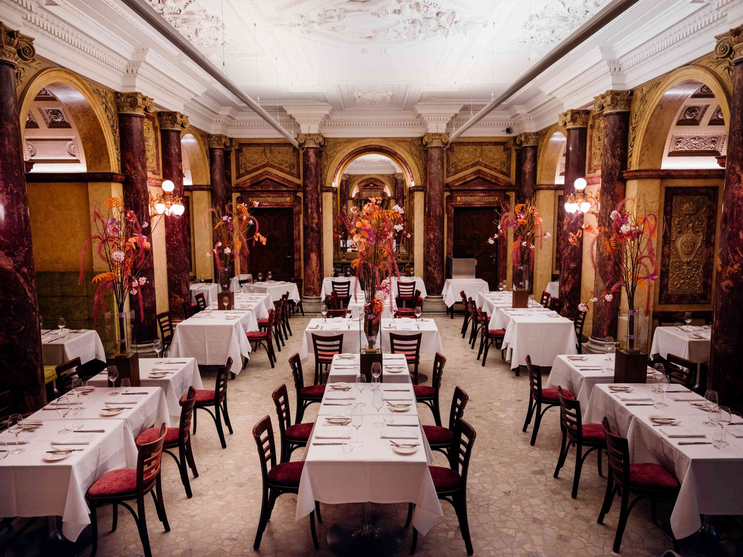 Klimatisierter Marmorsaal des Restaurants Vestibül im Wiener Burgtheater mit historischen Säulen und gedeckten Tischen.